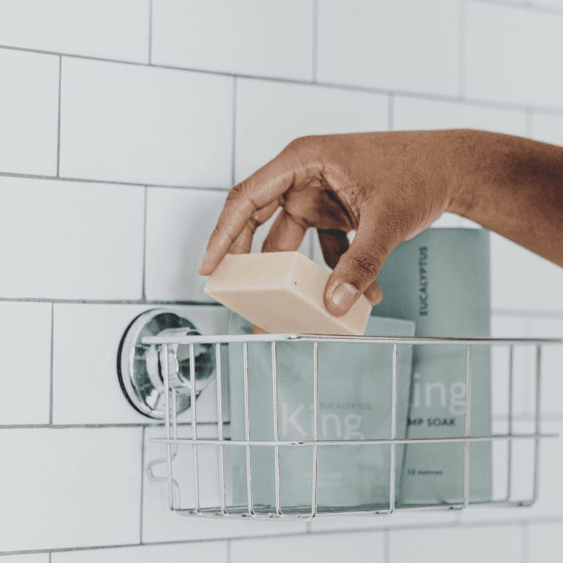 A man replacing his King body bar into the bath caddy on the shower.